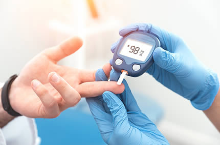 Hand eines Arztes bei der Blutzuckermessung am Patienten