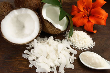 Frische Kokosnuss, Kokosflocken und Kokosöl auf dunklem Holz