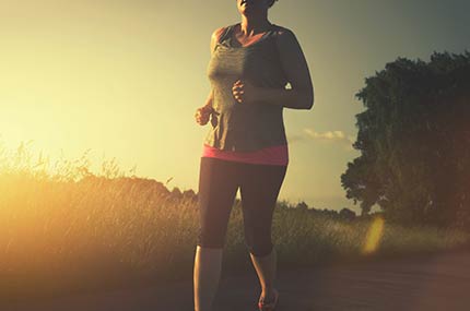 Joggende Frau im Sonnenuntergang auf dem Weg zur besseren Fitness