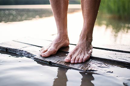 Männerbeine stehen auf einem Floß im Wasser – Natur erleben und entspannen