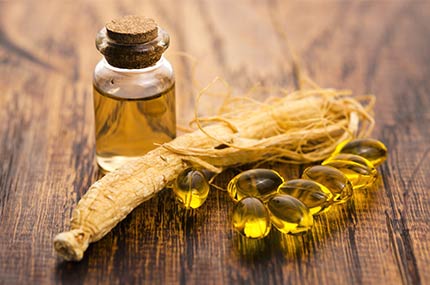 Fläschchen mit Ginsengöl, daneben Ginsengwurzel und passende Kapseln