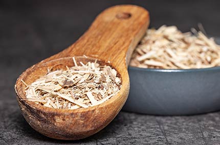 Holzlöffel mit getrocknetem Ginseng neben einer passenden kleinen Schale