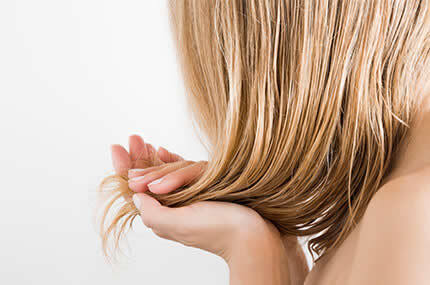 Blonde Haare, sanft von zwei Händen gehalten, symbolisieren Haarpflege