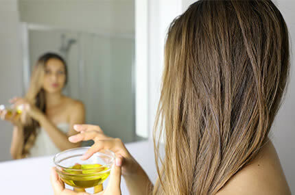 Frau hält Öl-Schälchen, symbolisiert intensive Haarpflege mit Conditioner und Öl