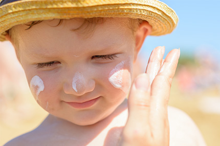 Kleines Kind hat Sonnencreme im Gesicht zum Schutz vor Sonne