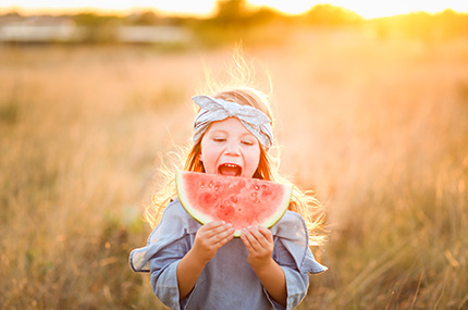Kind beißt genüsslich in eine saftige Wassermelone auf dem Feld
