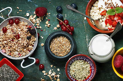 Nährstoffreiches Müsli-Arrangement mit Samen, Joghurt und Obst auf rustikalem Untergrund
